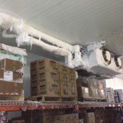 A warehouse with boxes and pipes on the ceiling.