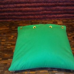 A green pillow sitting on top of a wooden floor.